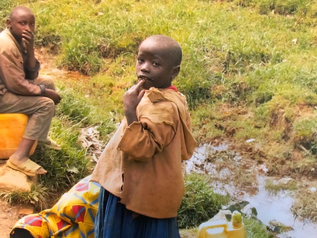Two children next to a stream of water and green grass