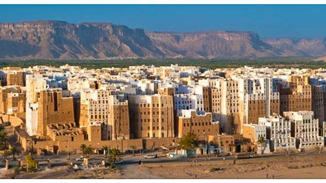 city with tall brown and white buildings and mountains in the back